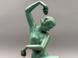 statue d'une femme assise sur un rocher, tenant une fleur dans la main droite
