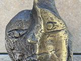 statue of a cat on a pedestal with a stone wall in the background