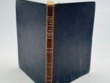 un livre bleu à la couverture marron et à la reliure dorée