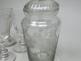 a glass jar with a lid sitting next to two wine glasses