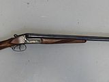 Le pistolet est accroché au mur, à côté du mur blanc.