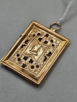 a close up of a gold pendant with a cross on it