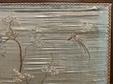 une photo d'un tableau représentant des oiseaux et des fleurs accroché au mur