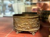 a gold bowl sitting on top of a table next to a clock