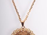 a close up of a gold necklace with a coin on it