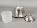 a silver cup and saucer on a table next to a glass