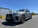 une voiture grise garée dans un parking à côté d'un bâtiment