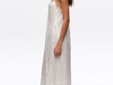 a woman in a white dress and sandals standing in front of a white background