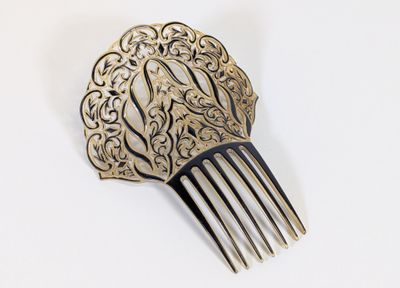 un peigne en argent orné d'un motif sur un fond blanc