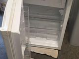 un petit réfrigérateur blanc, la porte ouverte, à côté des toilettes