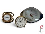 three clocks sitting next to each other on a white surface
