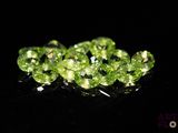 a close up of a bunch of green diamonds on a black surface