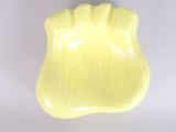 un bol jaune posé sur une surface blanche