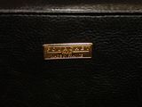 the back of a black purse with a gold plate on it