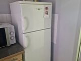a white refrigerator in a small kitchen with a microwave on top of it