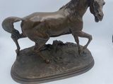 deux statues en bronze représentant un cheval et un oiseau, posées sur une surface blanche