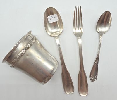 une cuillère, une fourchette et une tasse en argent posées sur une table