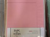 a pile of pink and green sheets on a bed