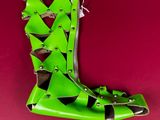 lime green leather boot with studs and rivets on a red background