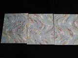three pieces of blue and white marbled paper on a black background
