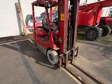 a red fork lift truck parked in front of a building