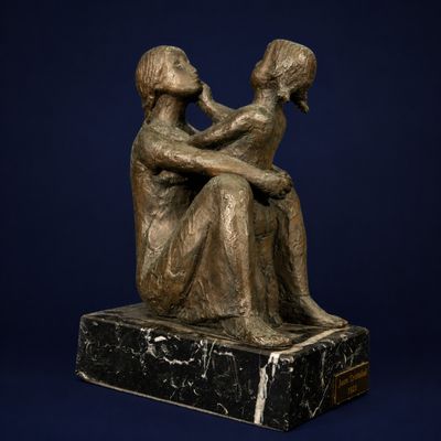 statue en bronze représentant un homme et une femme assis sur un socle en marbre