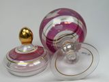 a pink and gold glass object with a gold lid