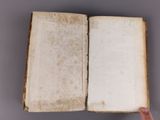 someone is holding a book open on a gray surface