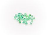 a pile of green emeralds on a white surface