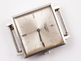 a silver square watch with a metal band on a white surface