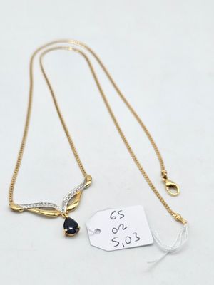 un collier en or orné d'une médaille et d'une petite pierre noire