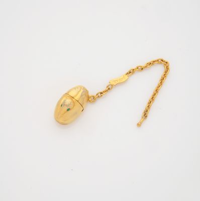 an image of a gold egg charm on a chain on a white surface