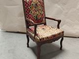 une vieille chaise dont le dossier et l'assise sont recouverts d'un tissu à motifs floraux