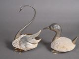 pair of silver plated swan figurines on a grey background