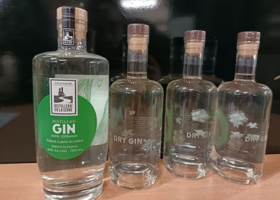 quatre bouteilles de gin sont alignées sur une table en bois