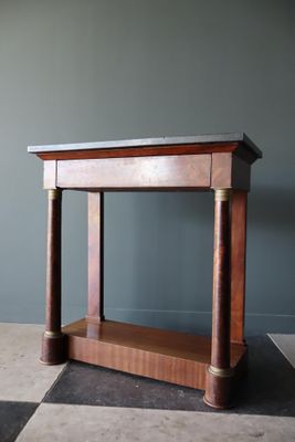 une image représentant une table en bois avec un plateau en marbre, posée sur un sol à damier noir et blanc