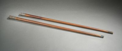 deux aiguilles à tricoter en bois posées sur une table, sur fond blanc