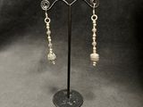 a pair of earrings on a stand with a black background