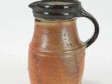 a brown pitcher with a black lid on a white surface