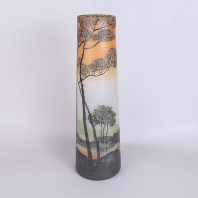 a tall vase with a painting of trees on it