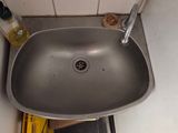 a sink in the corner of a bathroom with a soap dispenser