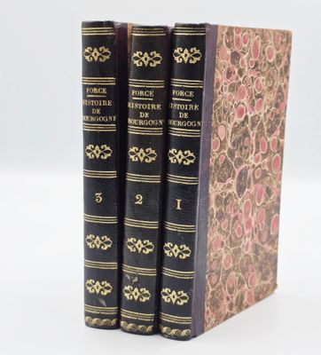 trois livres sont empilés sur une surface blanche