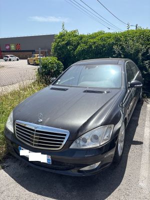 a black car parked in a parking lot next to a hedge