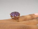 someone is holding a ring with a purple stone on it