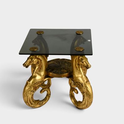 an image of a table with a glass top and two golden horses on it