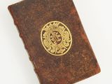an old book with a gold emblem on it sitting on top of a white surface