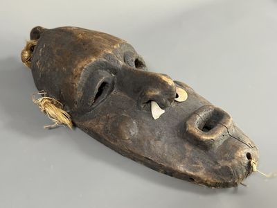 un vieux masque en bois posé sur une table, entouré d'une corde