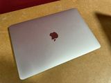 an apple laptop sitting on a table with a shadow on the table