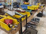 Plusieurs bacs contenant des outils sont alignés sur un établi dans un atelier.