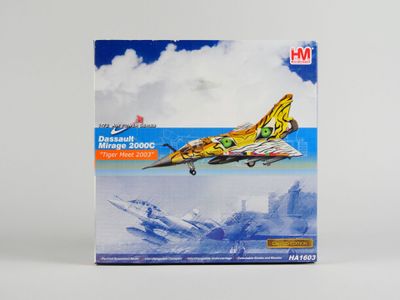 La boîte contient une maquette d'un avion de chasse volant dans le ciel.